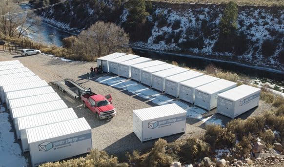 A red truck parked in front of several white storage containers.