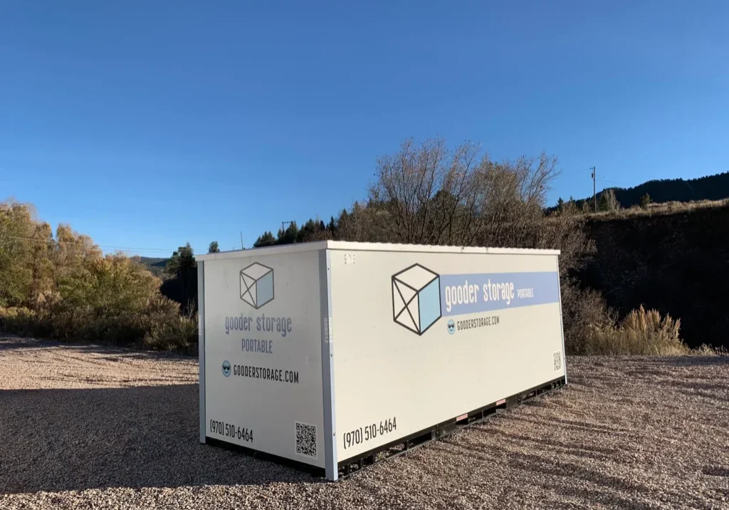 Portable storage box on a gravel pad Gooder box sitting on a gravel pad under a clear blue sky, with fall trees and hills behind it