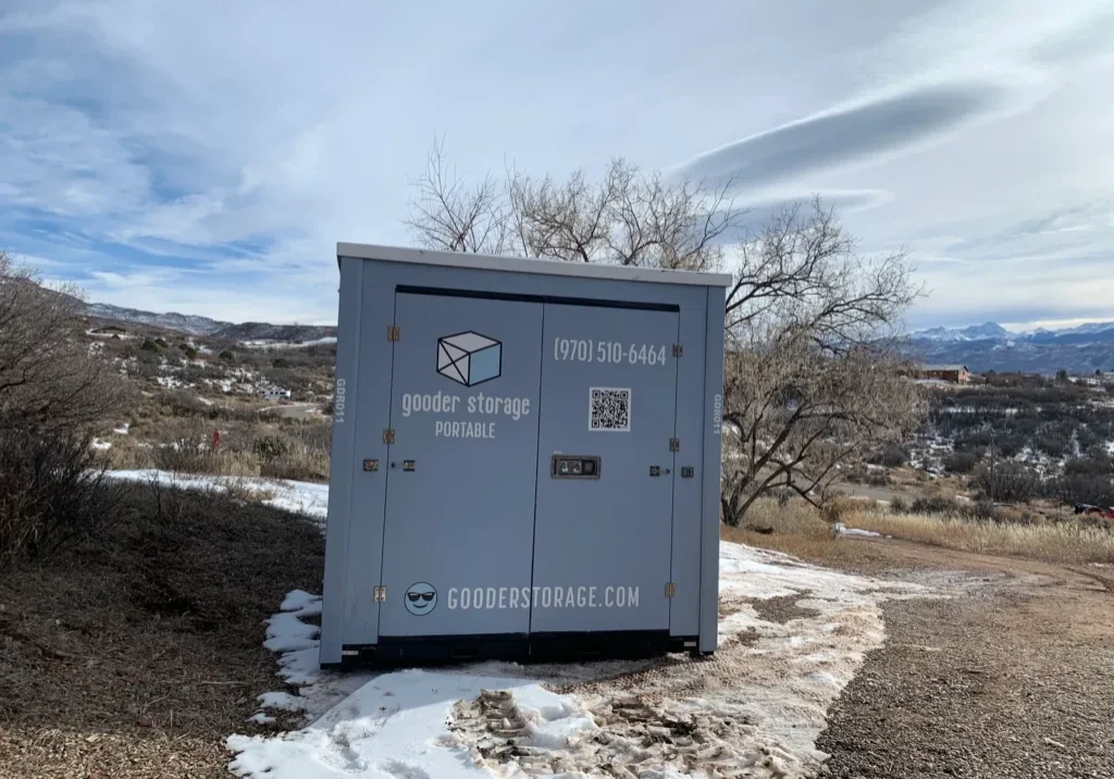 Portable storage box on a snowy hillside Gooder box on a snowy hillside lot with bare trees and snow-capped mountains in the distance